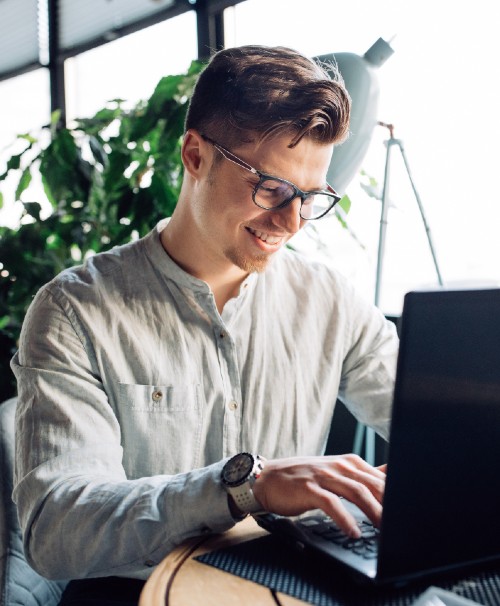 young IT professional smiling at laptop